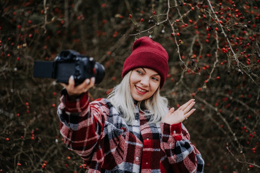 smiling travel blogger woman making new video blog vlog with her camera on nature forest background t20 O0ZmKE